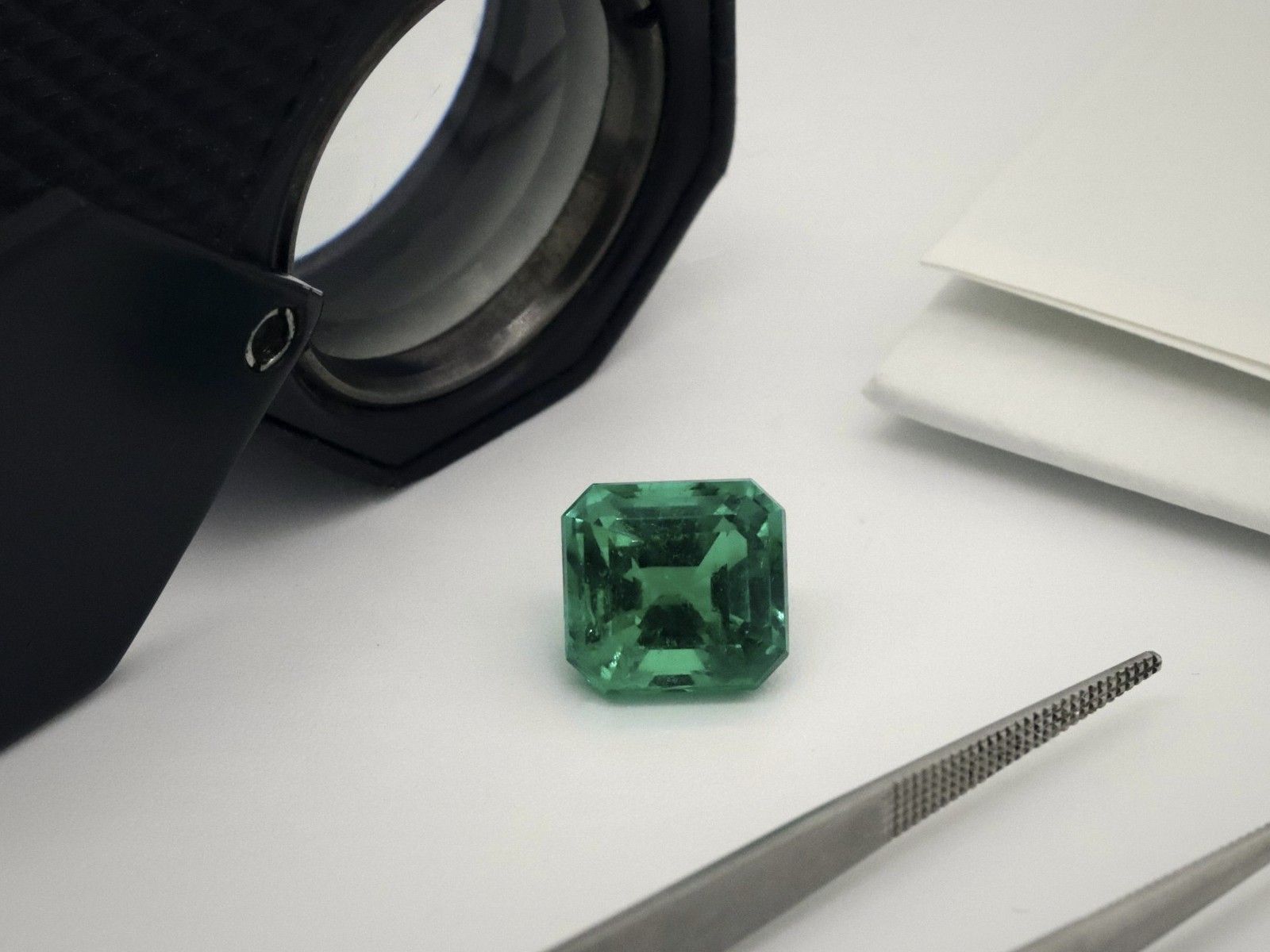 Emerald with a loupe and tweezers on a grading table
